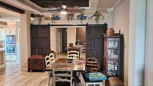 A spacious dining area with a wooden table and chairs, a large cabinet with glass doors, and a ceiling fan.