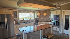 A modern kitchen with a central island, stainless steel appliances, and pendant lighting.