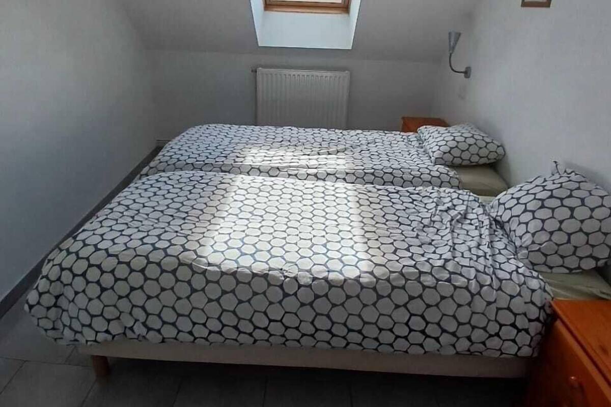 A bedroom with a skylight, a bed with patterned bedding, a radiator, and a bedside table.