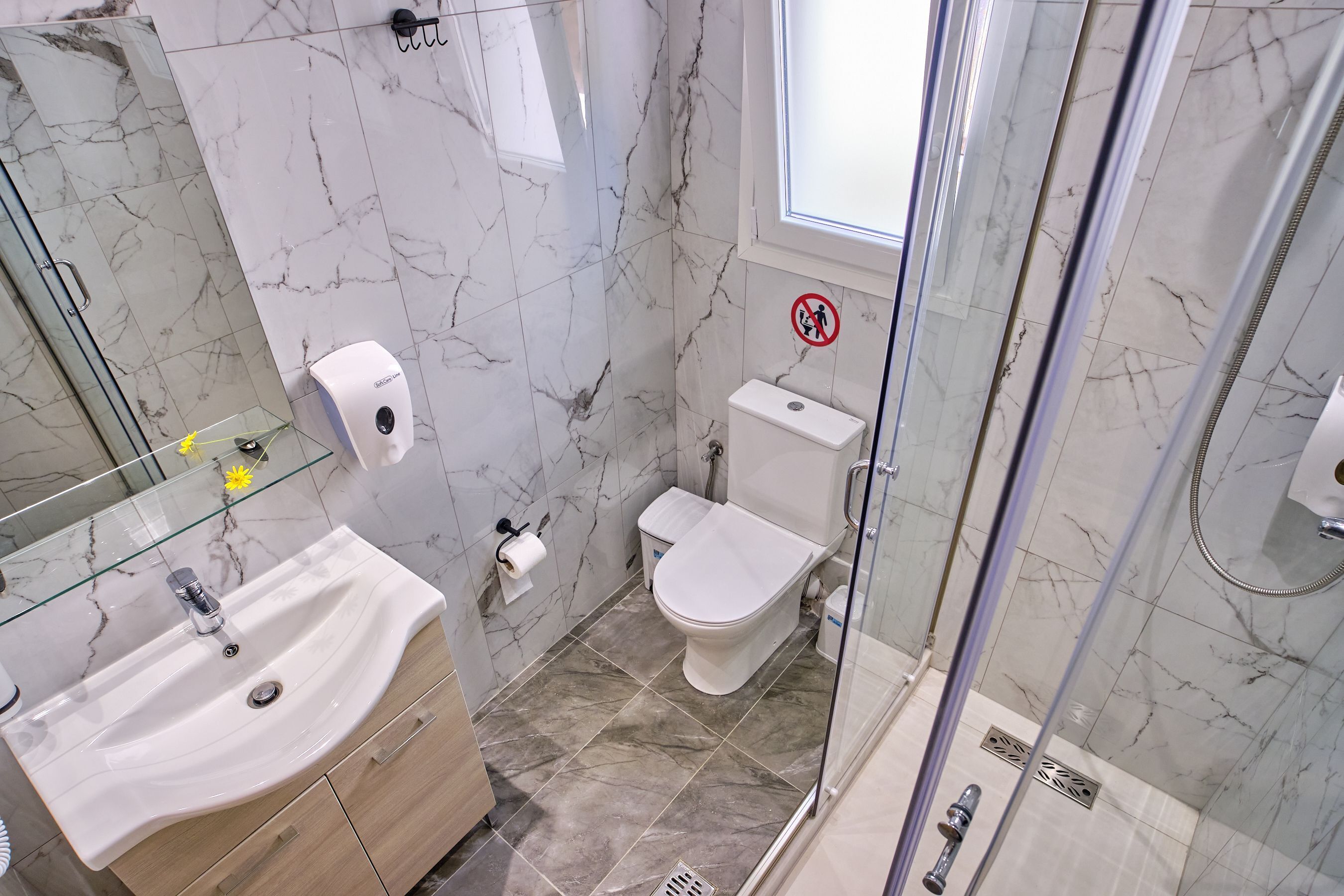 Un bagno con box doccia in vetro, lavabo in marmo e water.