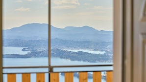 Vistes panoràmiques a través d'una finestra, amb un llac, muntanyes i una ciutat al fons.
