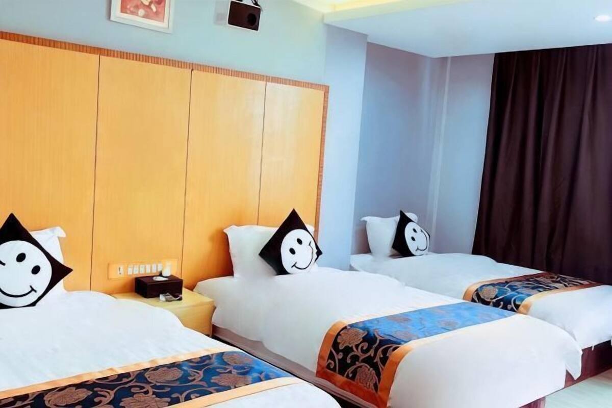 A hotel room with three beds, each with a pillow featuring a cartoon face.