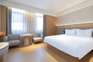 A hotel room with a large bed, two armchairs, a small table, and a window with curtains. - Hotels in Werner (Yangxi)