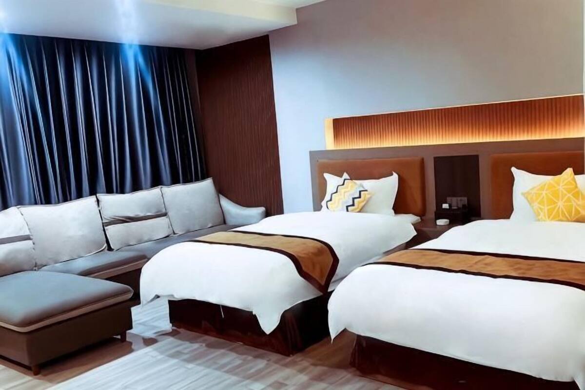 A hotel room with a large bed, a sofa bed, a desk, and a nightstand.