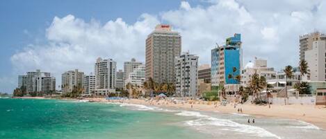 Un paisaje urbano costero con edificios altos, una playa y cielos despejados.