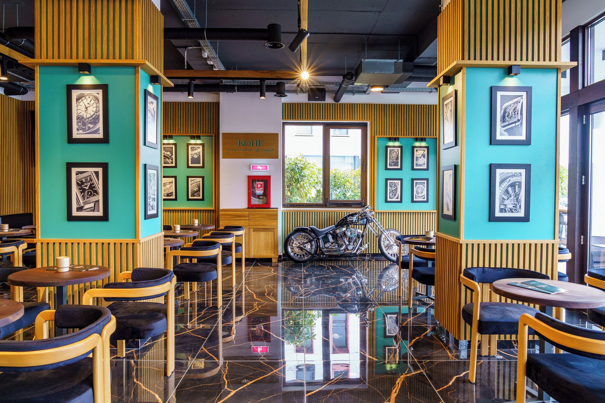 Un café avec des boiseries, des œuvres d’art encadrées accrochées aux murs et une moto au centre.