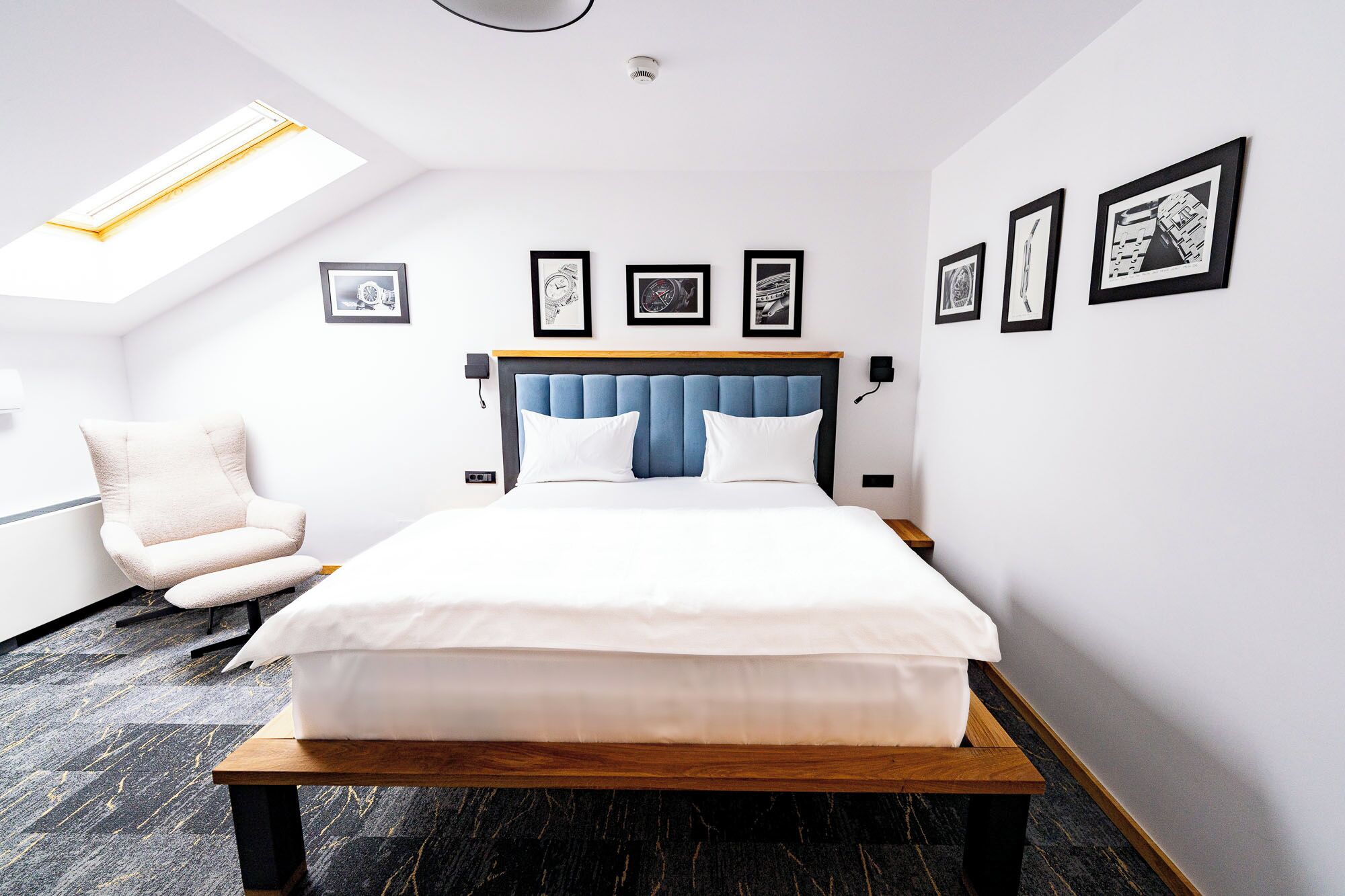 Quarto de hotel moderno com cama, uma cadeira e quadros na parede.