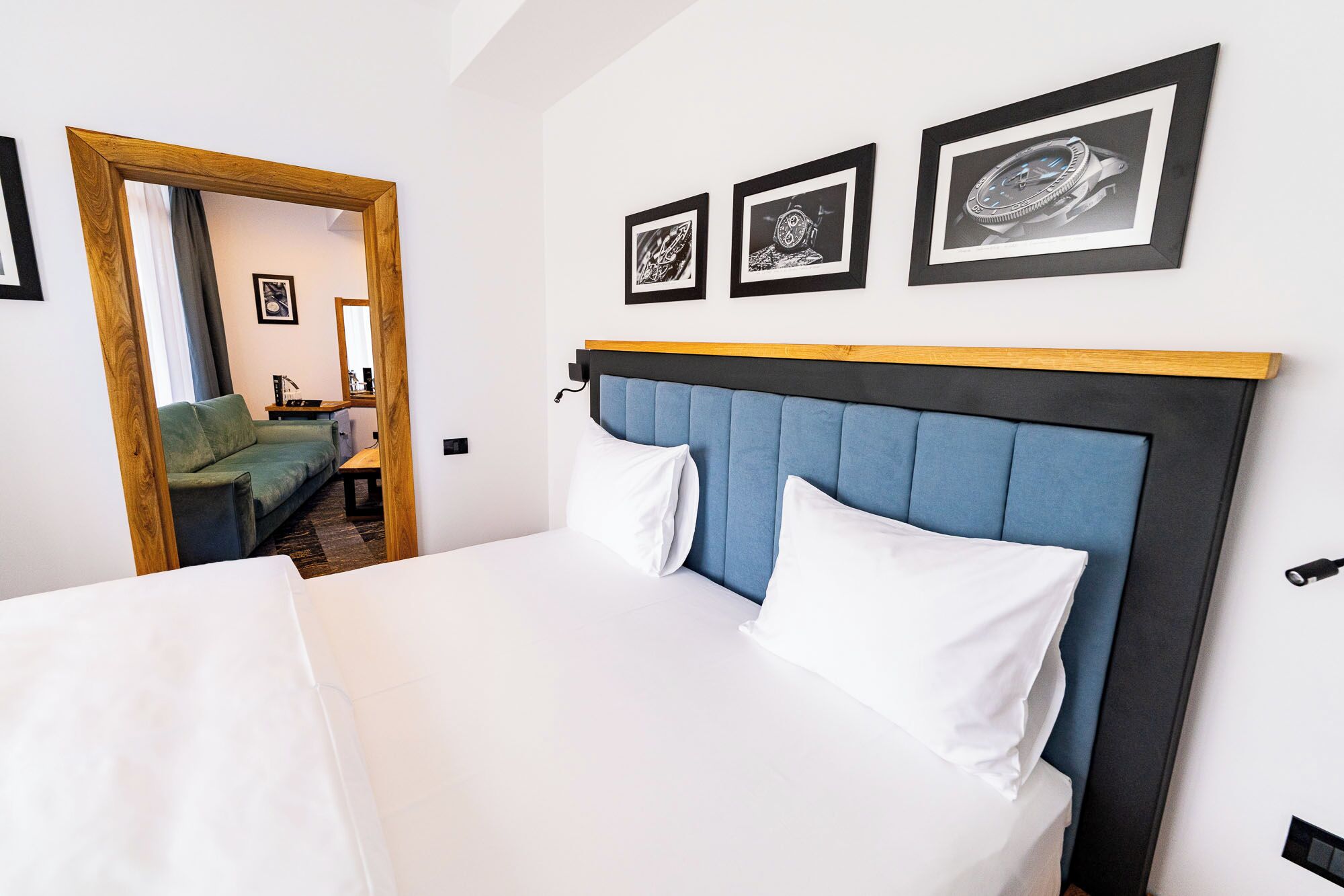 Una habitación de hotel con una cama, cabecera de madera y tres cuadros en la pared.