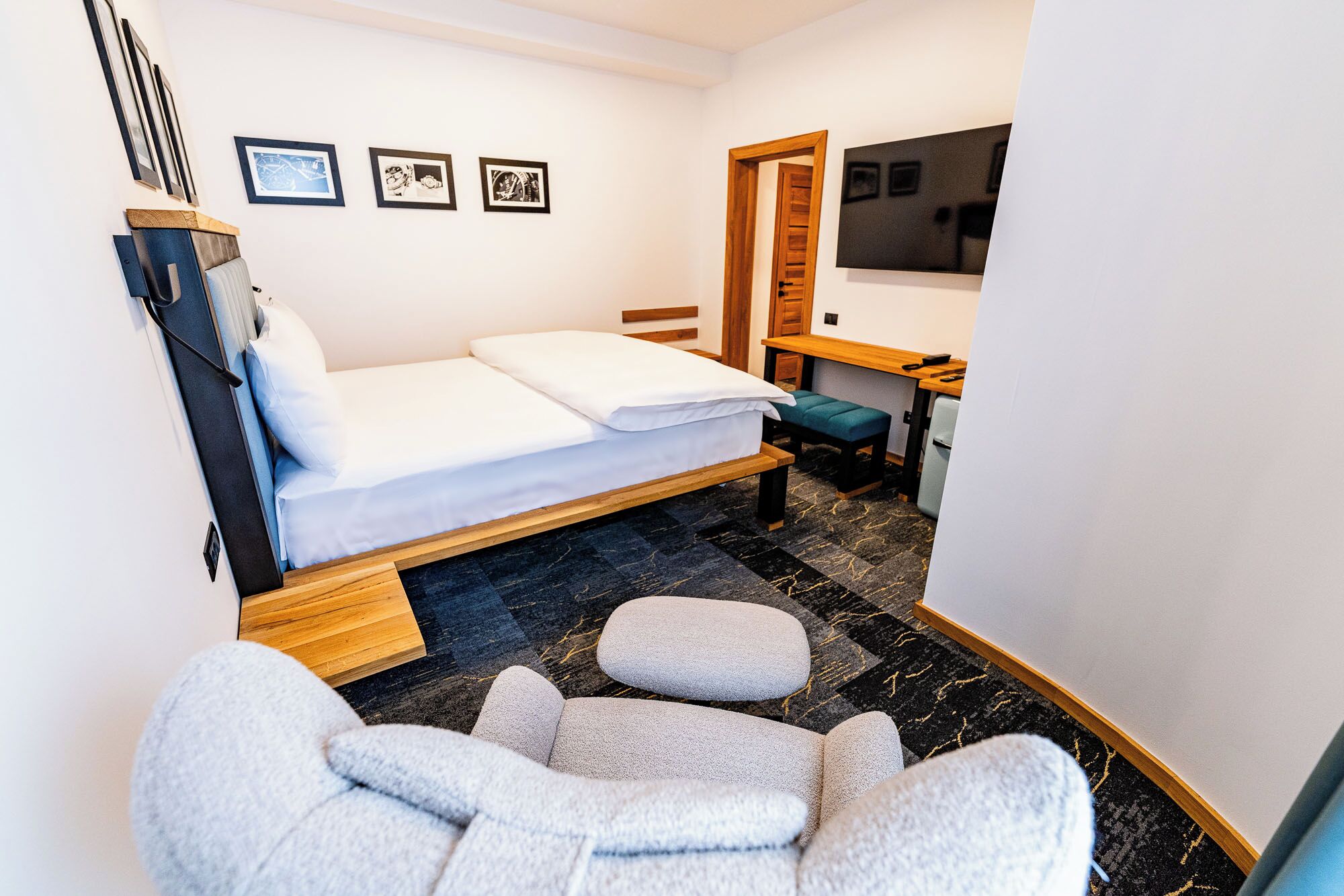 Quarto de hotel pequeno com uma cama de solteiro, uma mesa, uma cadeira e uma televisão.
