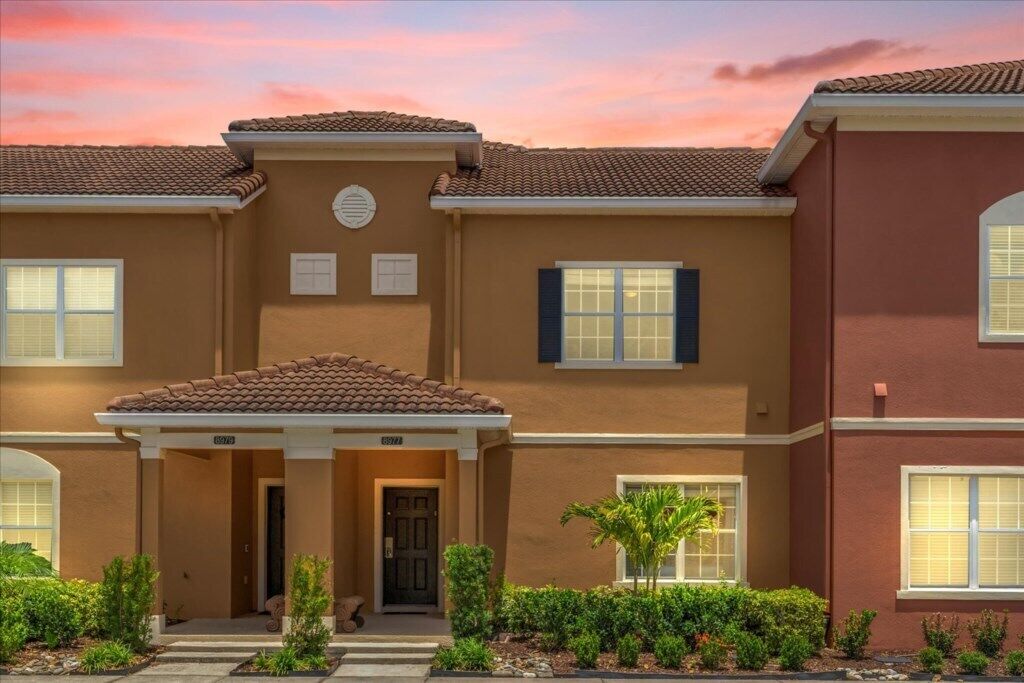 A two-story building with a tiled roof, a covered entrance, and a landscaped front yard.