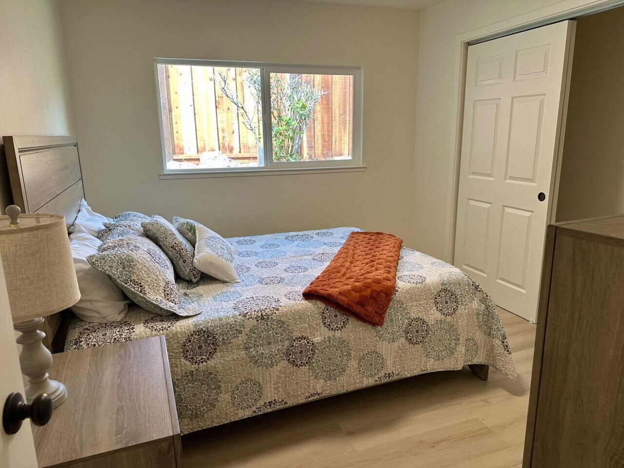 A bedroom with a bed, a window, and a door.