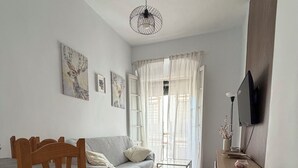 Habitació amb llit, una cadira de fusta, una taula petita, televisió i obra d'art a les parets.