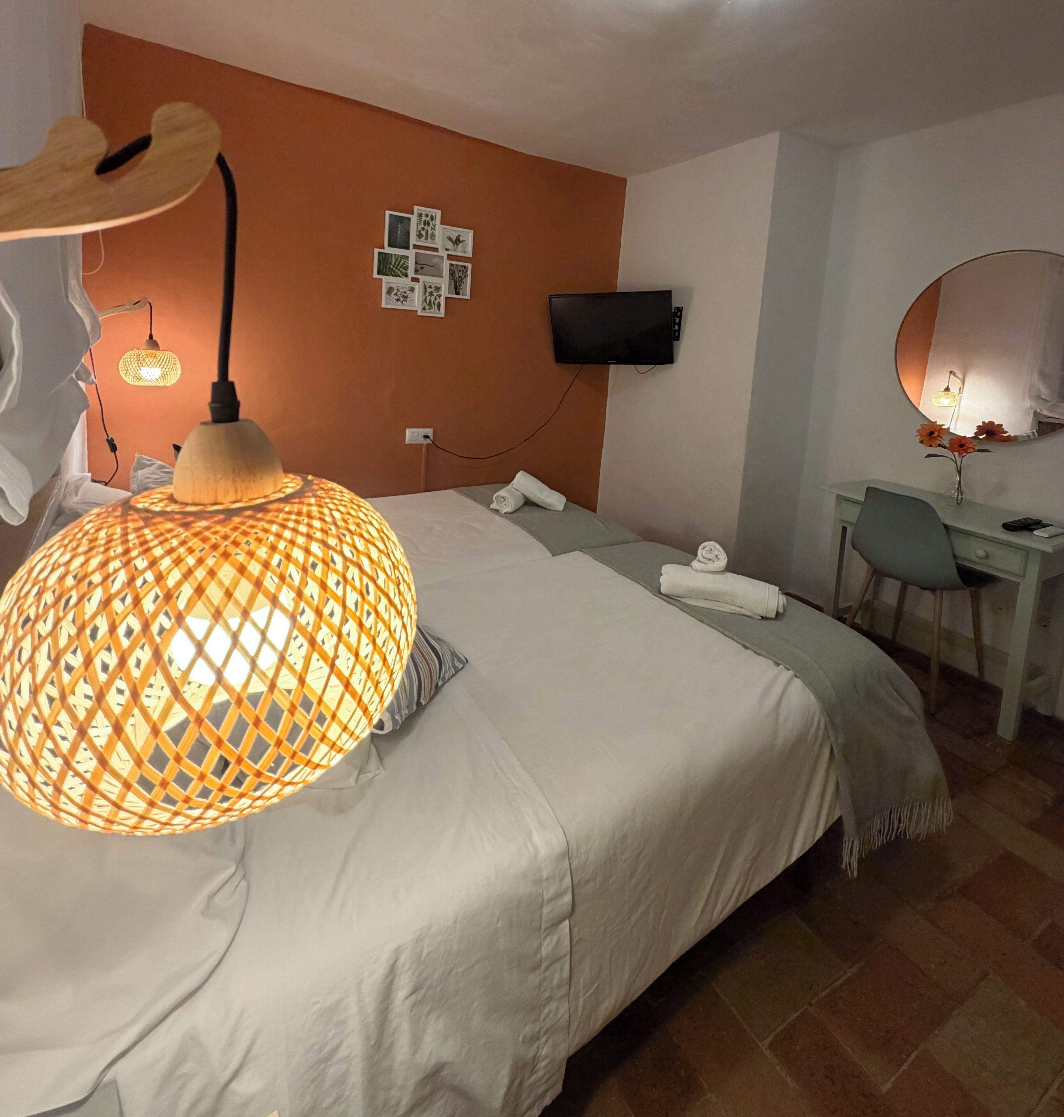 A hotel room with a bed, a desk, a TV, and a wall-mounted mirror.
