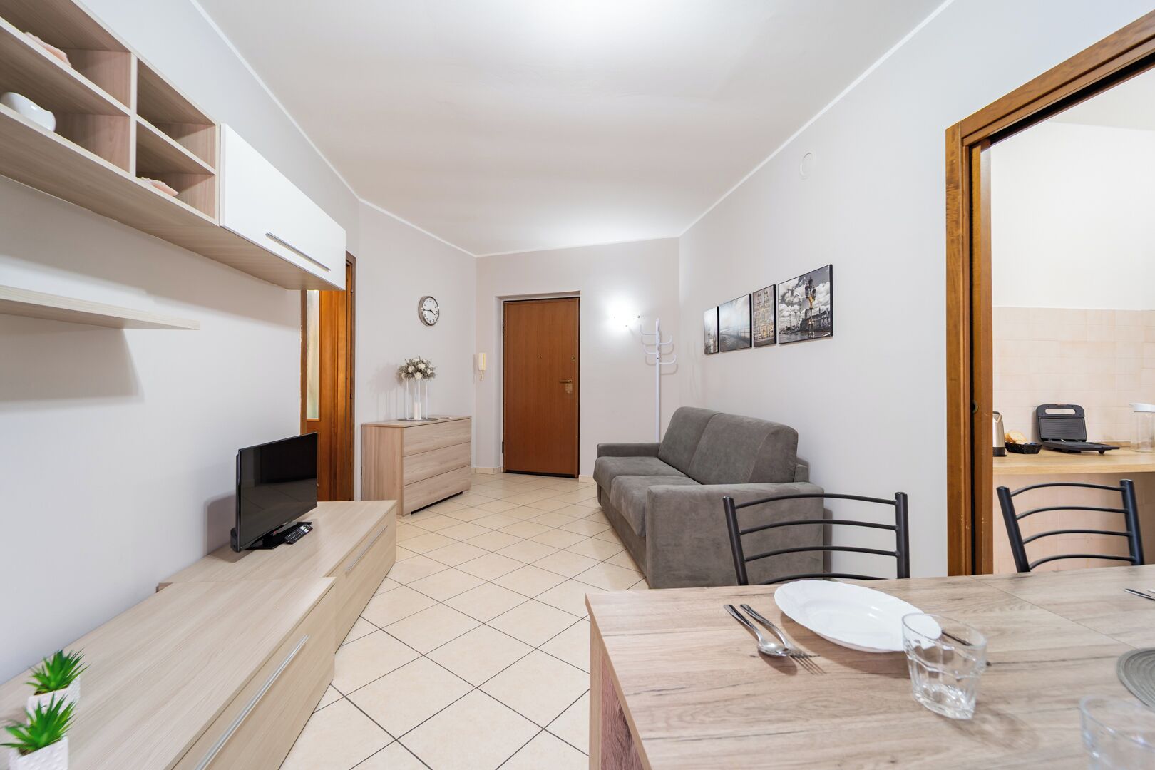 Een modern appartement met een eethoek, een bank, een televisie en een kitchenette.