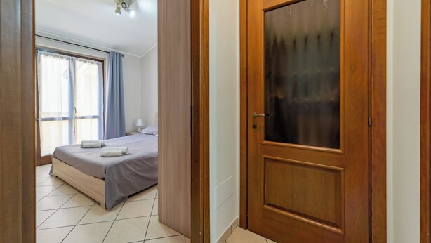 A hotel room with a bed, a nightstand, a lamp, and a window with curtains.