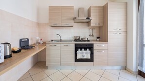 A modern kitchen with light wood cabinetry, a stainless steel sink, a gas stove, and a built-in oven.