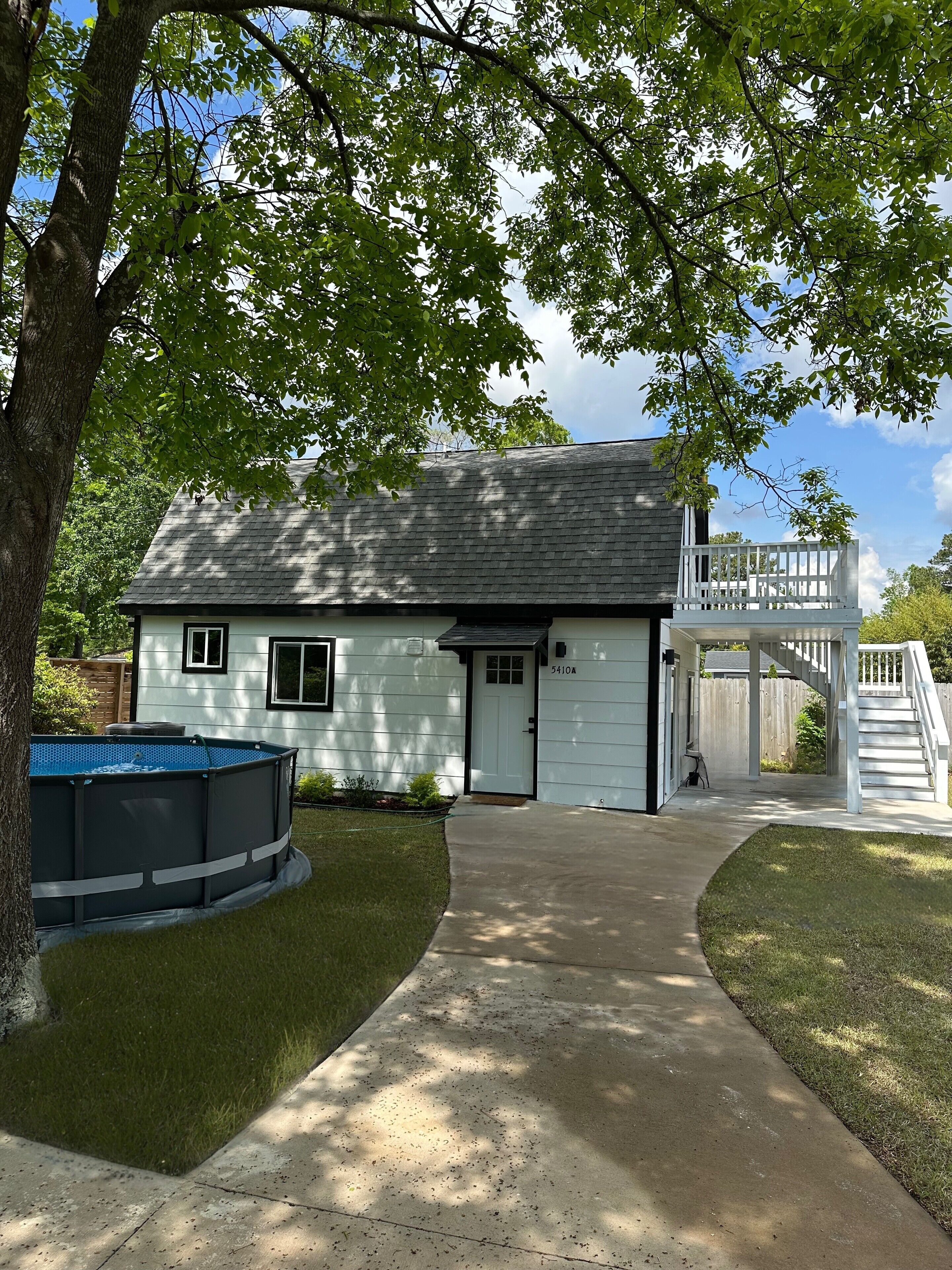 A house with a covered porch, a swimming pool, and a well-maintained lawn.