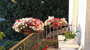 A balcony with a tiled floor, potted plants, a metal railing, and a table with chairs. - Luminous Viola room with artistic light - Madame Fanny (Lucca)