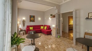 A living room with a red sectional sofa, a dining table, and a chandelier. - Luminous Viola room with artistic light - Madame Fanny (Lucca)