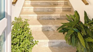 A staircase with marble steps, wooden handrails, and potted plants at the bottom. - Luminous Viola room with artistic light - Madame Fanny (Lucca)