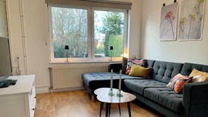A modern living room with a grey sofa, a small round table with candles, and a white desk. - Bungalow in Sint Maartenszee Near Beach (Sint Maartensvlotbrug)