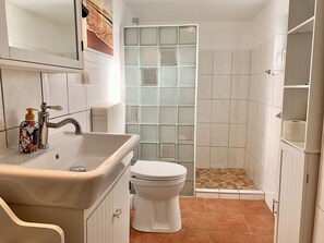 Un baño pequeño con lavamanos, inodoro y zona de ducha.