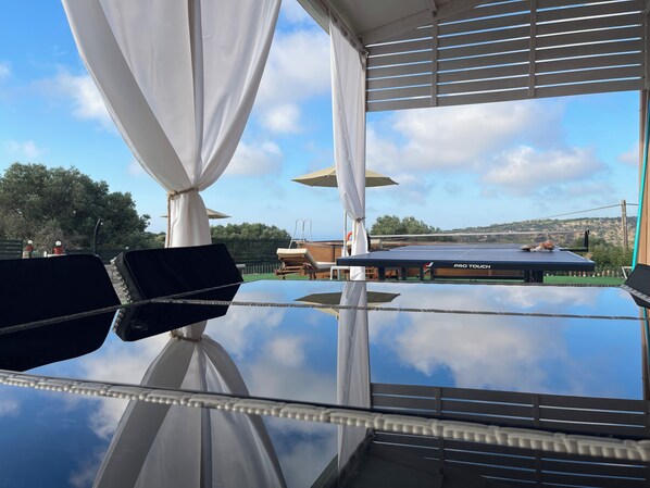A table with a tennis net, a pro touch table, and outdoor seating with umbrellas.