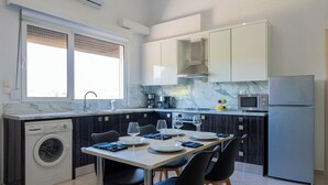 Cozinha moderna com máquina de lavar embutida, mesa de jantar para quatro pessoas e geladeira.