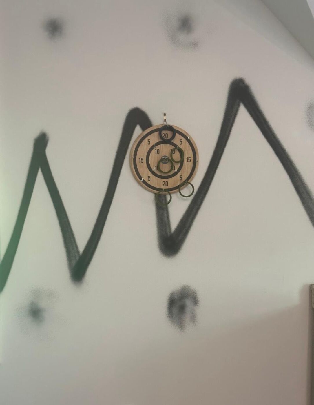 Un mur amb un objecte circular i un dibuix en zig-zag verd.