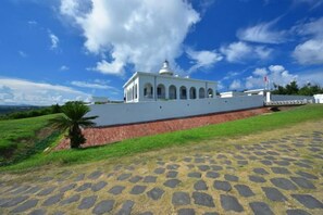 A white building with a dome and arched windows, situated on a paved area with a palm tree nearby. - Kenting Nanwan 254 (Pingtung)