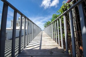 A wooden boardwalk with metal railings, leading to a building with a white facade. - Kenting Nanwan 254 (Pingtung)