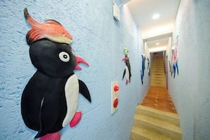 A hallway with a large penguin decoration, a staircase, and a wall-mounted light switch. - Kenting Nanwan 254 (Pingtung)