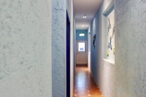 A hallway with a tiled floor, a door at the end, and a window with a view. - Kenting Nanwan 254 (Pingtung)