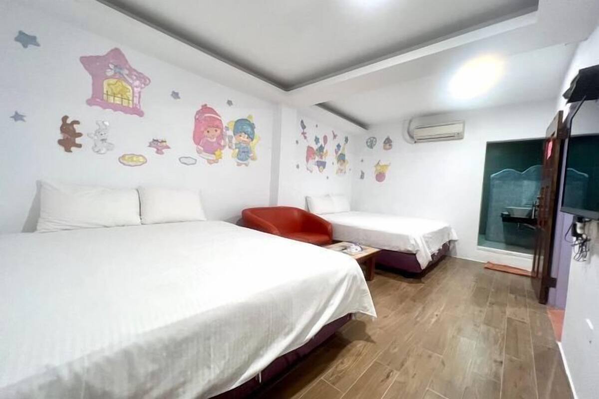 Una camera d'albergo con due letti, una sedia rossa e decorazioni adesive al muro.