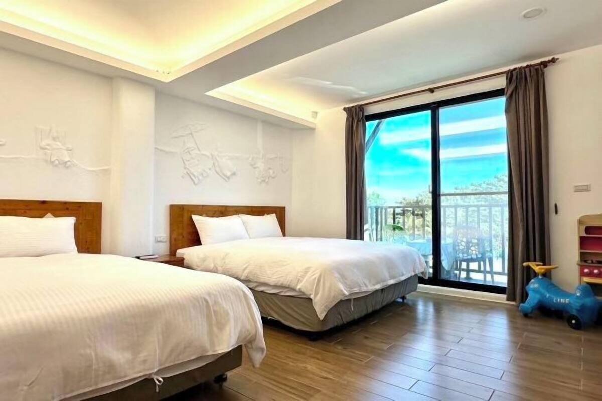 Camera d'albergo con due letti, un balcone e vista, e una macchinina giocattolo.