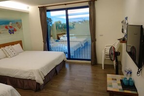 A hotel room with a bed, a desk with a chair, a television, and a view through a sliding glass door. - Kenting Nanwan 254 (Pingtung)