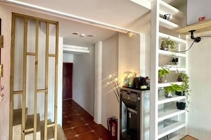 A hallway with a wooden partition, a kitchen area with a stove, and a shelving unit with plants. - Kenting Nanwan 254 (Pingtung)