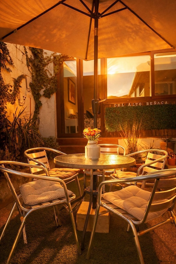 An outdoor patio with a round table, four chairs, and a vase with flowers.