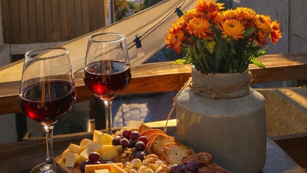 A table with a cheese board, wine glasses, and a vase of flowers. - Del Alto Reñaca Guest House (Viña del Mar)