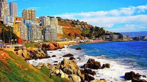 A coastal cityscape with high-rise buildings, rocky shoreline, and a clear blue sky. - Del Alto Reñaca Guest House (Viña del Mar)