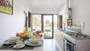 A modern kitchen with a gas stove, a dining area with breakfast items, and a view through the glass door. - Del Alto Reñaca Guest House (Viña del Mar)
