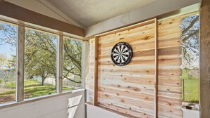 Ein Zimmer mit großen Fenstern, einer Dartscheibe und Holzvertäfelung.