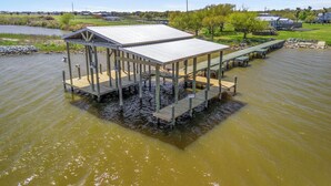 Eine Holzsteg mit einem überdachten Pavillon, umgeben von ruhigem Wasser und viel Grün.