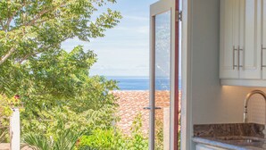 A kitchen with white cabinets and a view of a pool and greenery. - Villa Cielo Casita — Pool & Ocean View, Ocotal (Playa Azul, Ocotal)