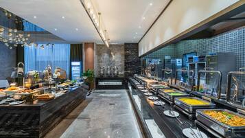 A buffet with various food stations, a coffee machine, and a decorative wall.