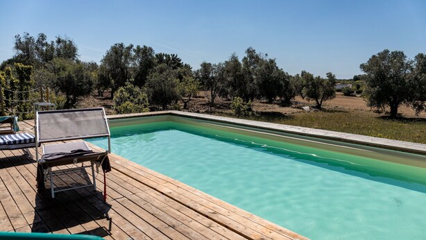 Une piscine rectangulaire à l’eau claire, entourée d’une terrasse en bois.