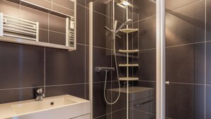A modern bathroom with a walk-in shower, a standalone sink, and a built-in toilet. - Cosy Renovated Flat on the Seafront (Koksijde)
