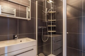 A modern bathroom with a walk-in shower, a standalone sink, and a built-in toilet.