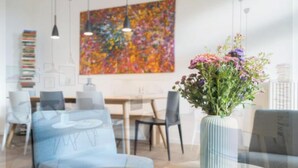 A modern interior with a dining area, a large abstract painting, and a vase with flowers. - Bright & Stylish Apartment in Berlin's Sprengelkiez (Berlin)