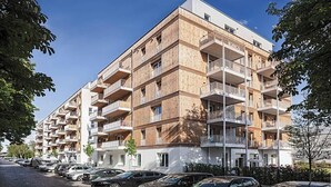 A multi-story residential building with balconies, a parking area in front, and a clear sky. - Bright & Stylish Apartment in Berlin's Sprengelkiez (Berlin)